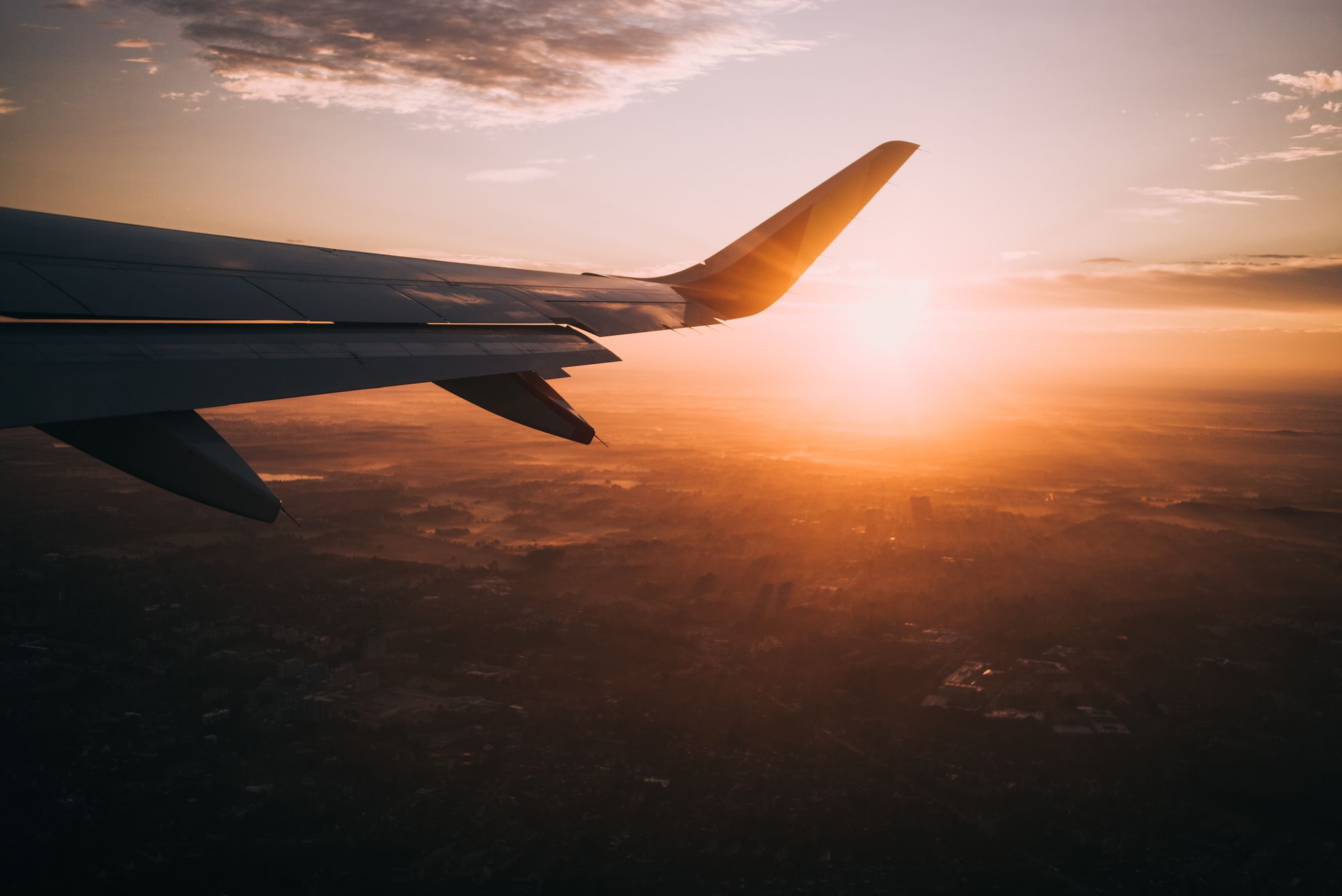 Flight booking tips while traveling on an airplane with a sunset background.